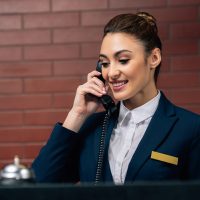 young beautiful hotel receptionist receiving call at workplace